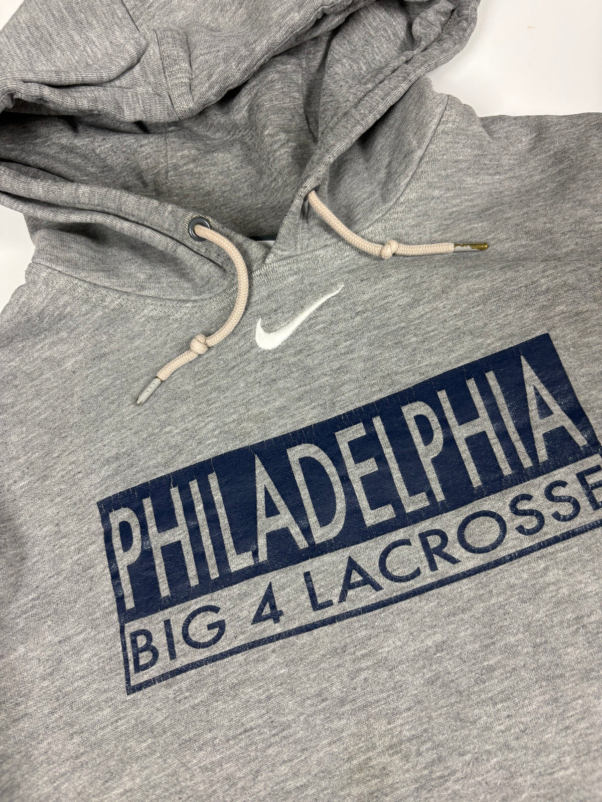 Nahaufnahme von Lacrosse-Print, weiß gesticktem Nike-Swoosh und beiger Kordel mit Metallenden