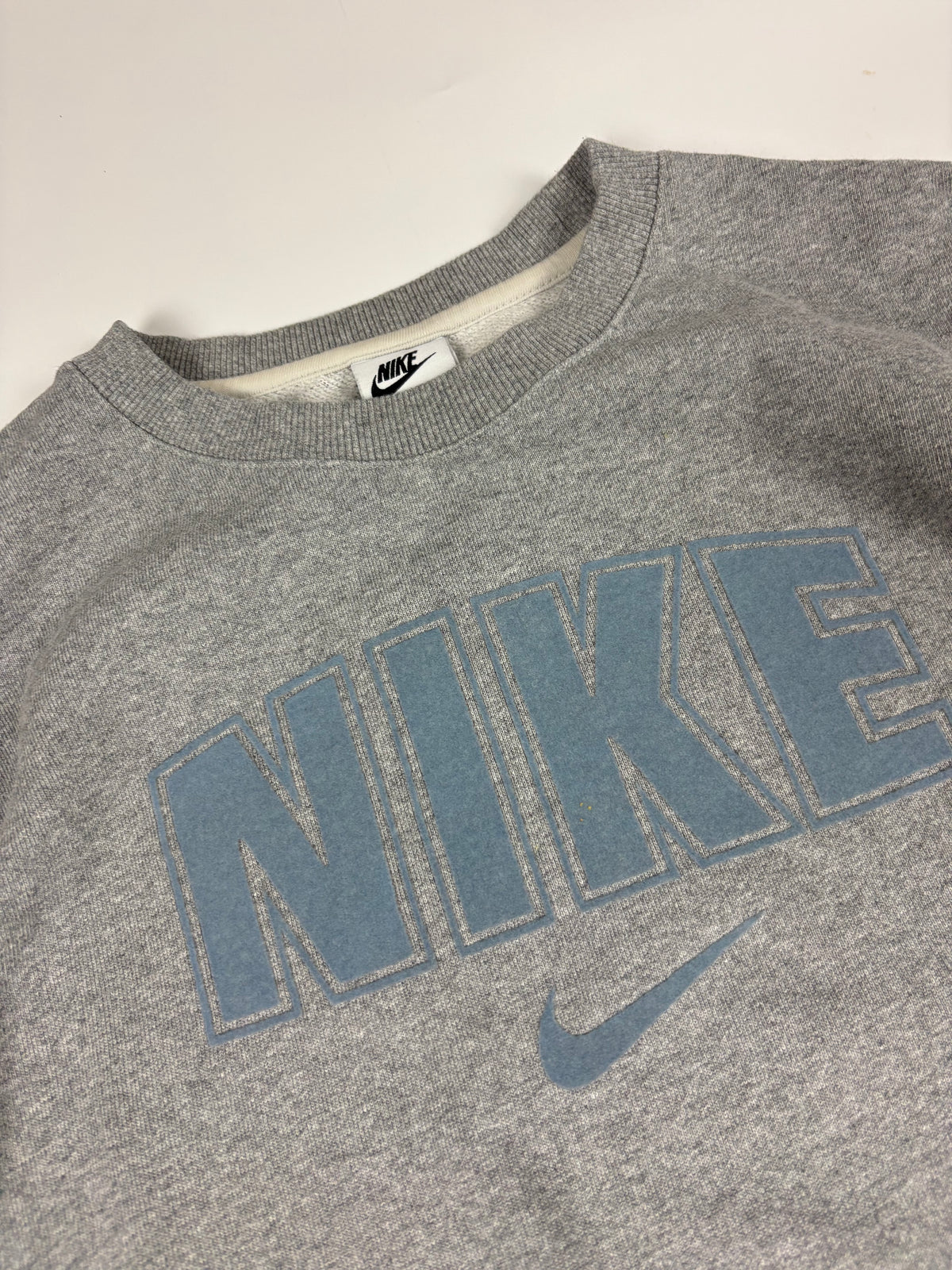 Hellblauer, geflockter NIKE-Schriftzug mit Swoosh und gerippter Kragen mit Nike-Halsetikett