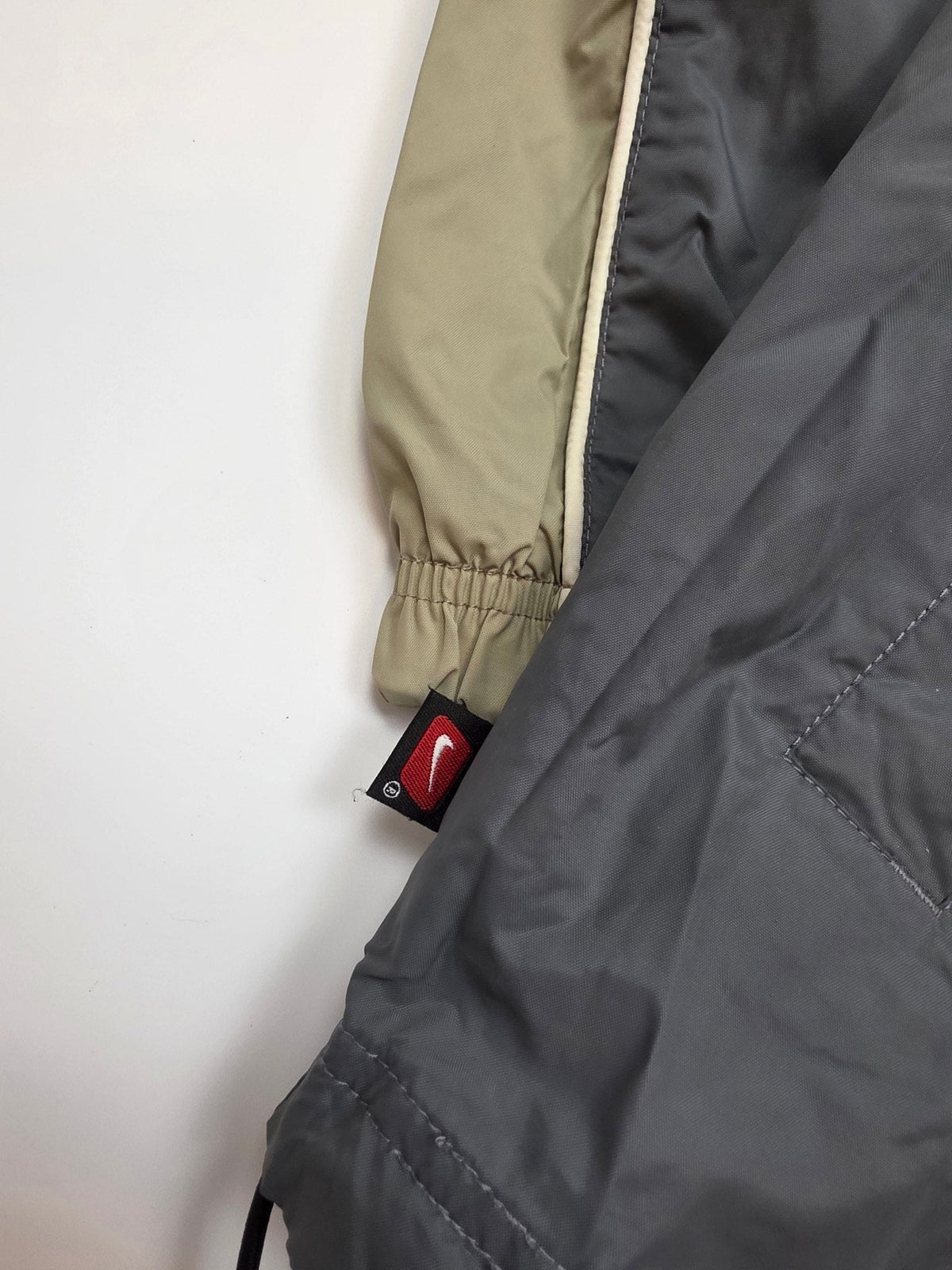 Rotes Nike Swoosh Logo-Tab am Saumbereich des grau-oliven Vintage Windbreakers