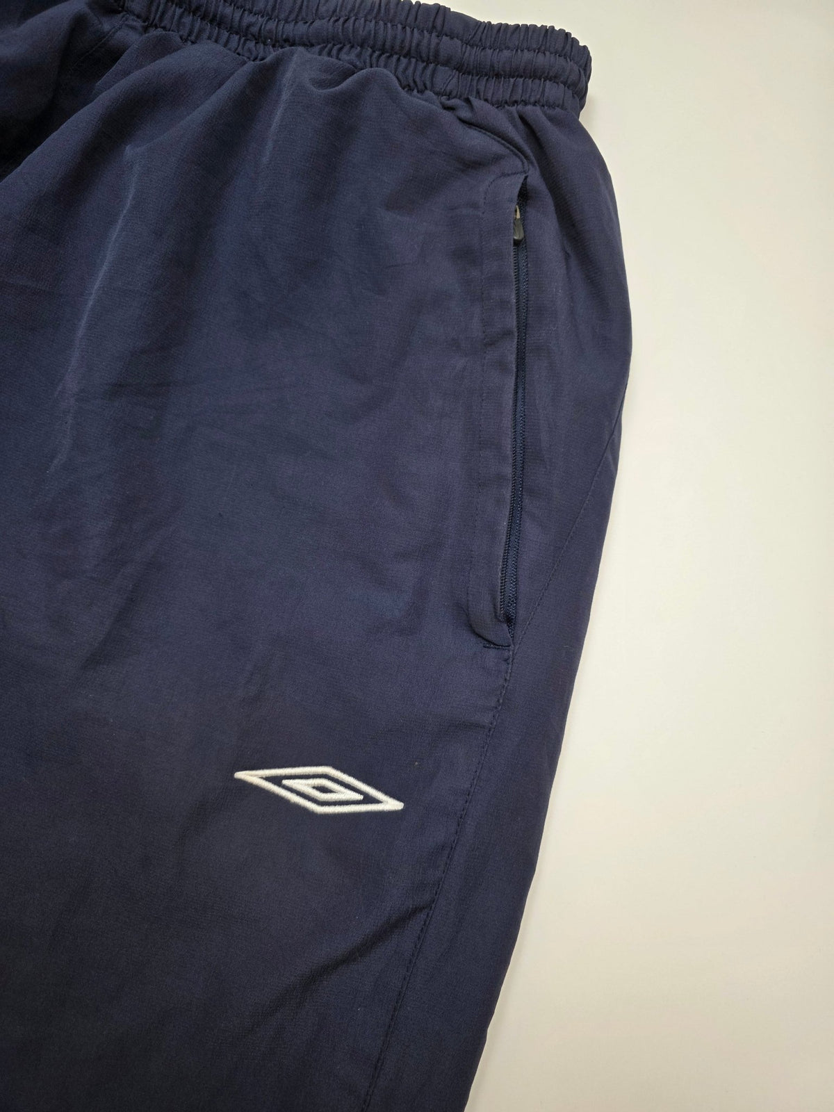 Detail des weißen Umbro Logos und der Zip-Tasche an den England Vintage Trackpants in Navy
