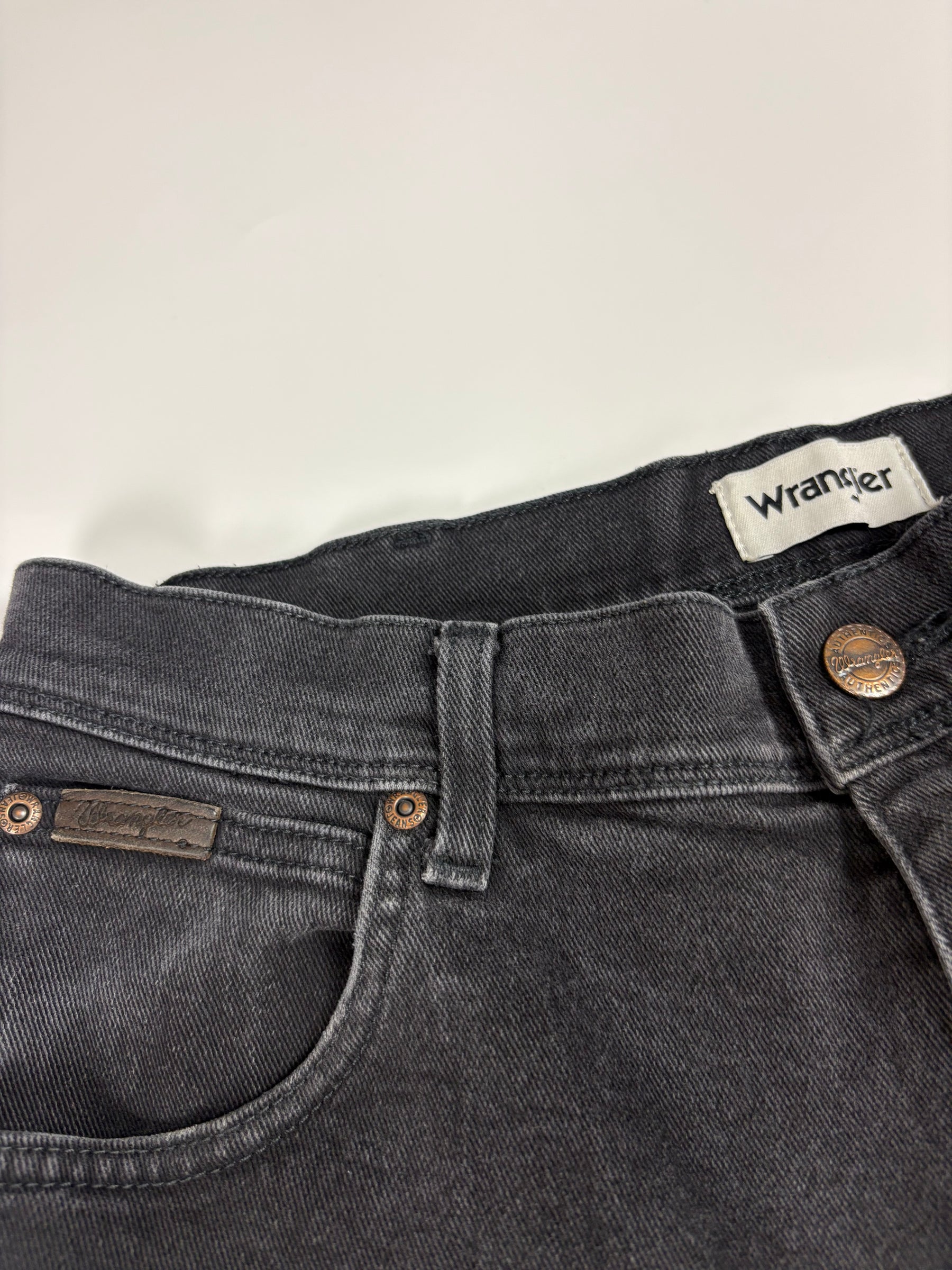 Detail des Wrangler Markenpatches und Bundbereichs an der schwarzen Vintage Jeans