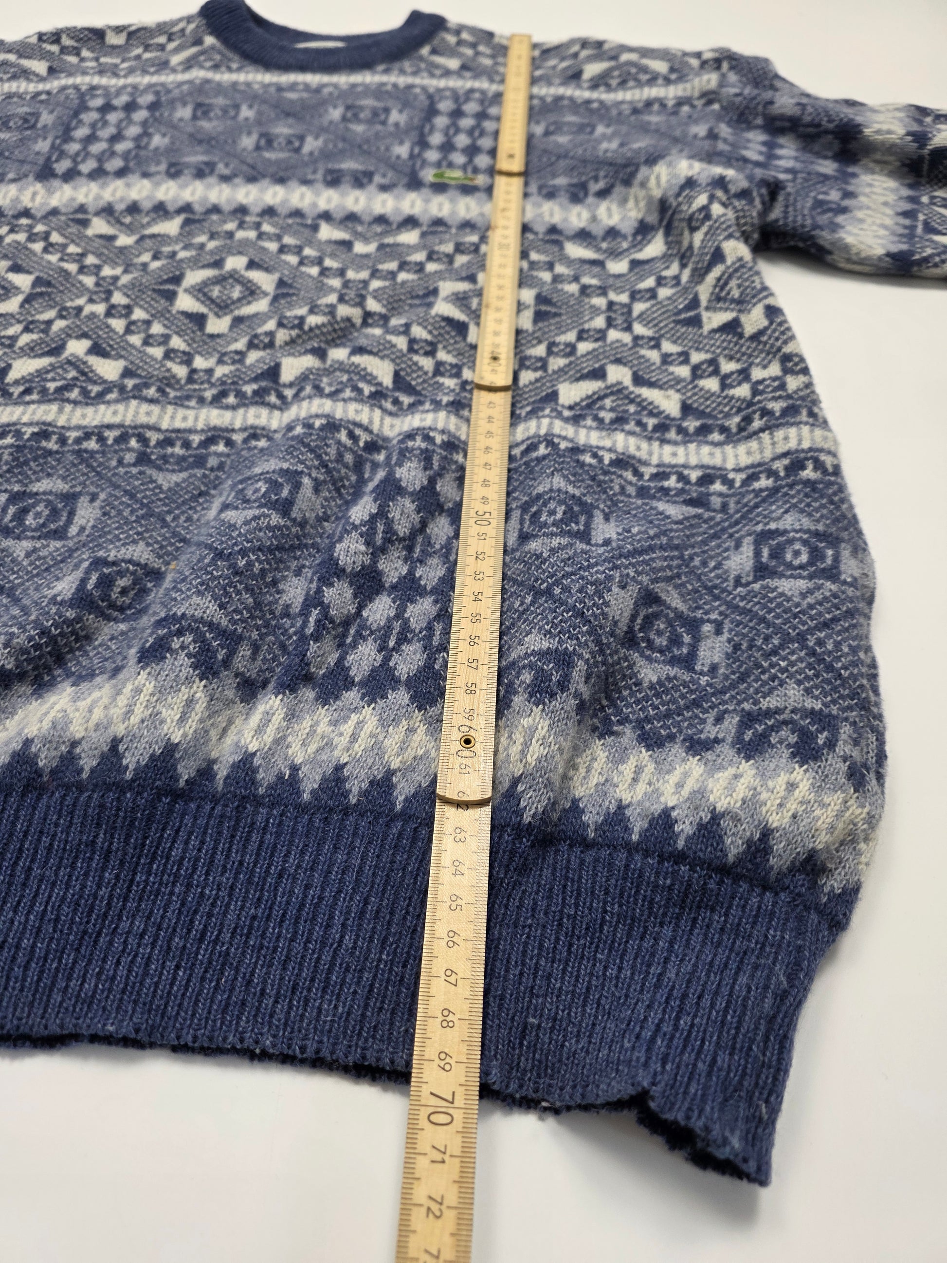 Blau-weißer Vintage-Strickpullover mit Norwegermuster, auf weißem Hintergrund mit Maßband.