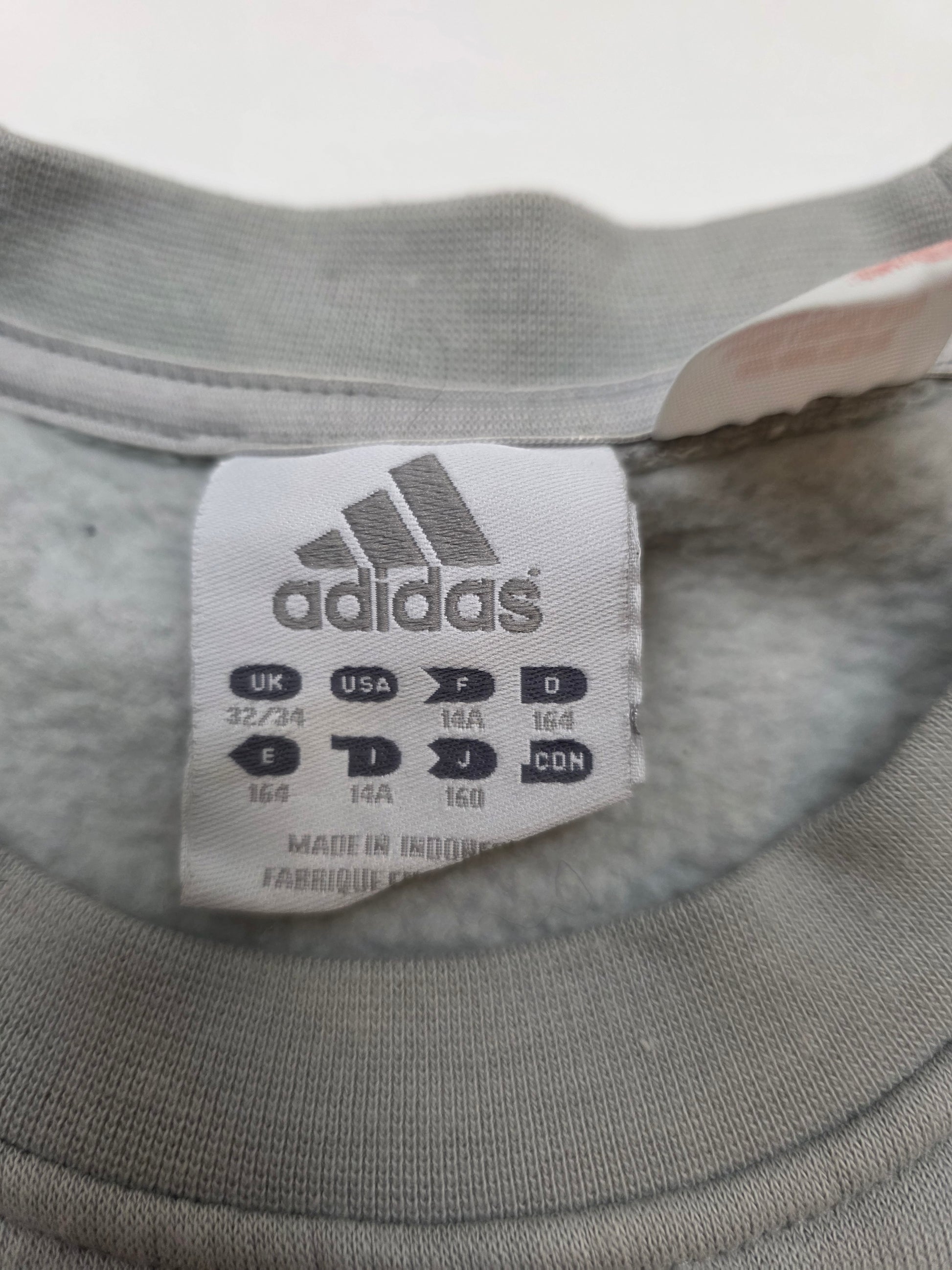 Grauer Vintage-Sweater mit adidas Größenschild, Retro-Sportswear Detailaufnahme