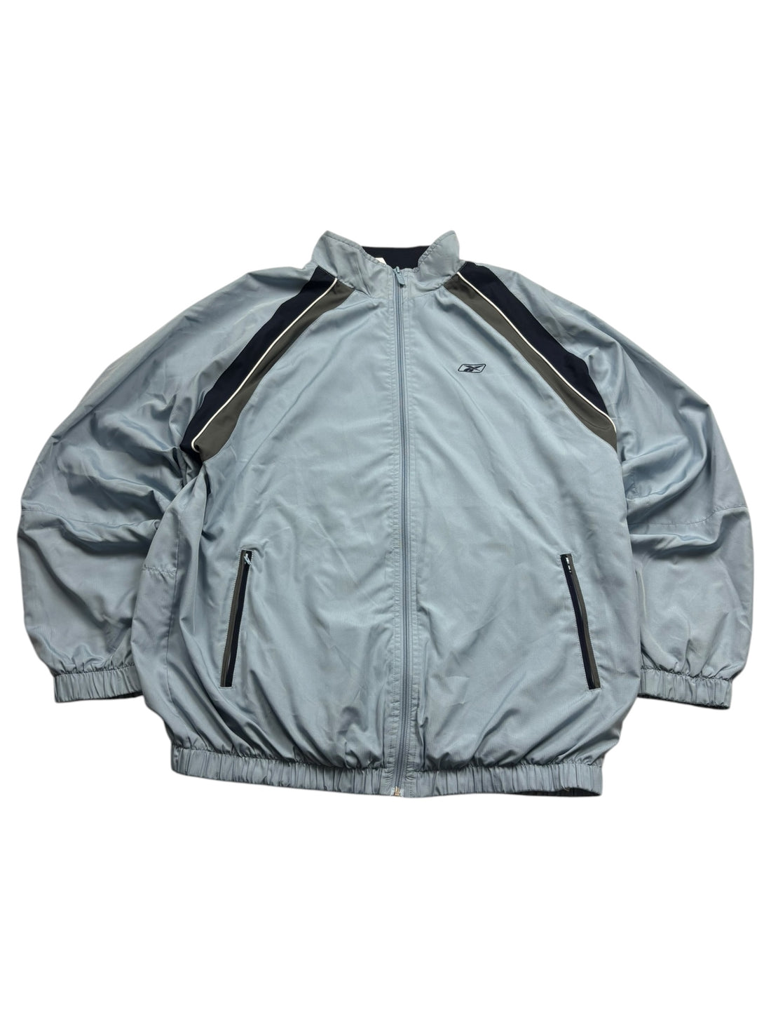 Reebok Vector 90s Tracksuit Jacke Hellblau Größe XL – Frontansicht mit dunklen Einsätzen und weißem Piping