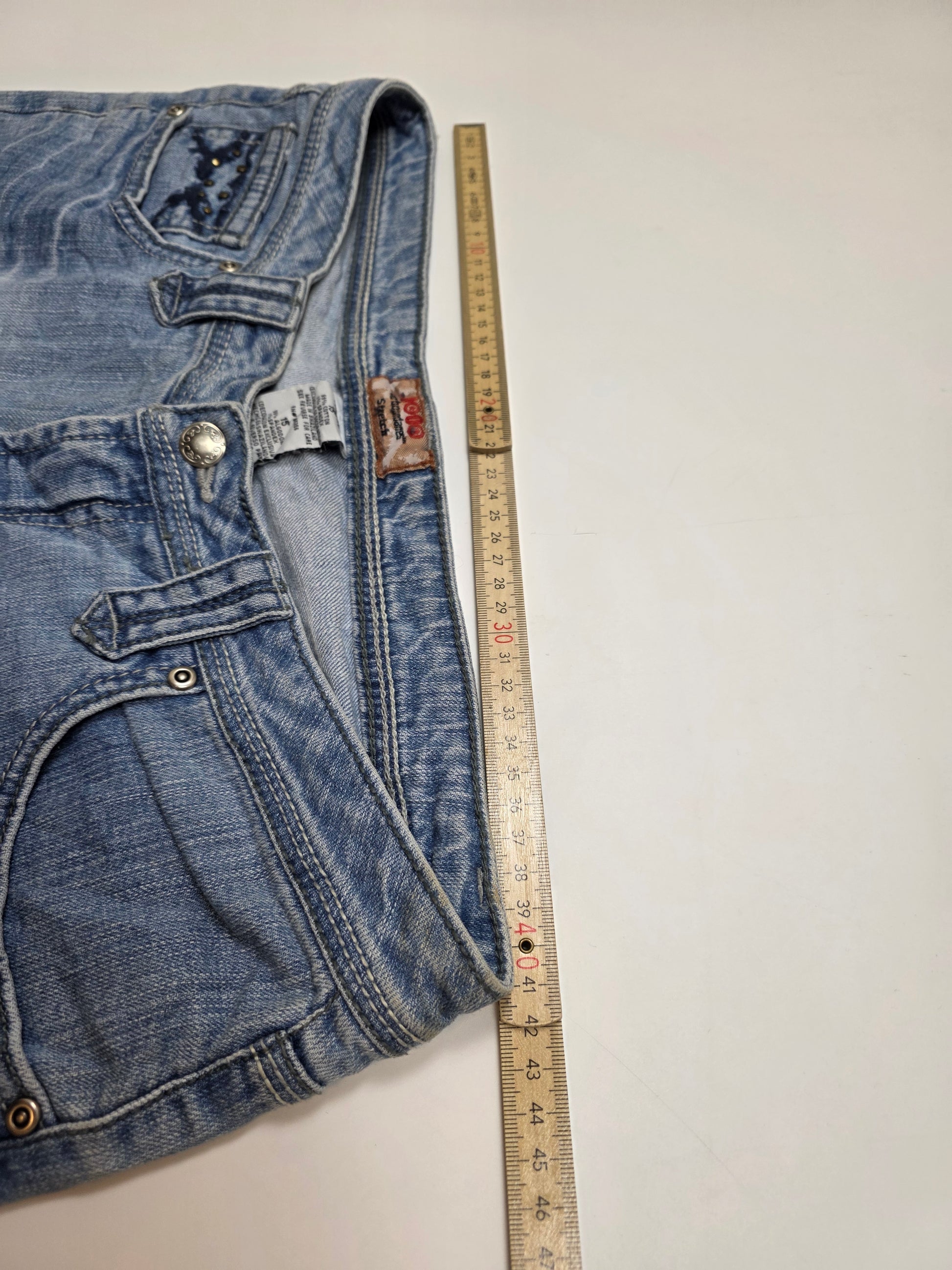 Vintage Jeans in Hellblau mit Maßband zur Größenbestimmung auf weißem Hintergrund
