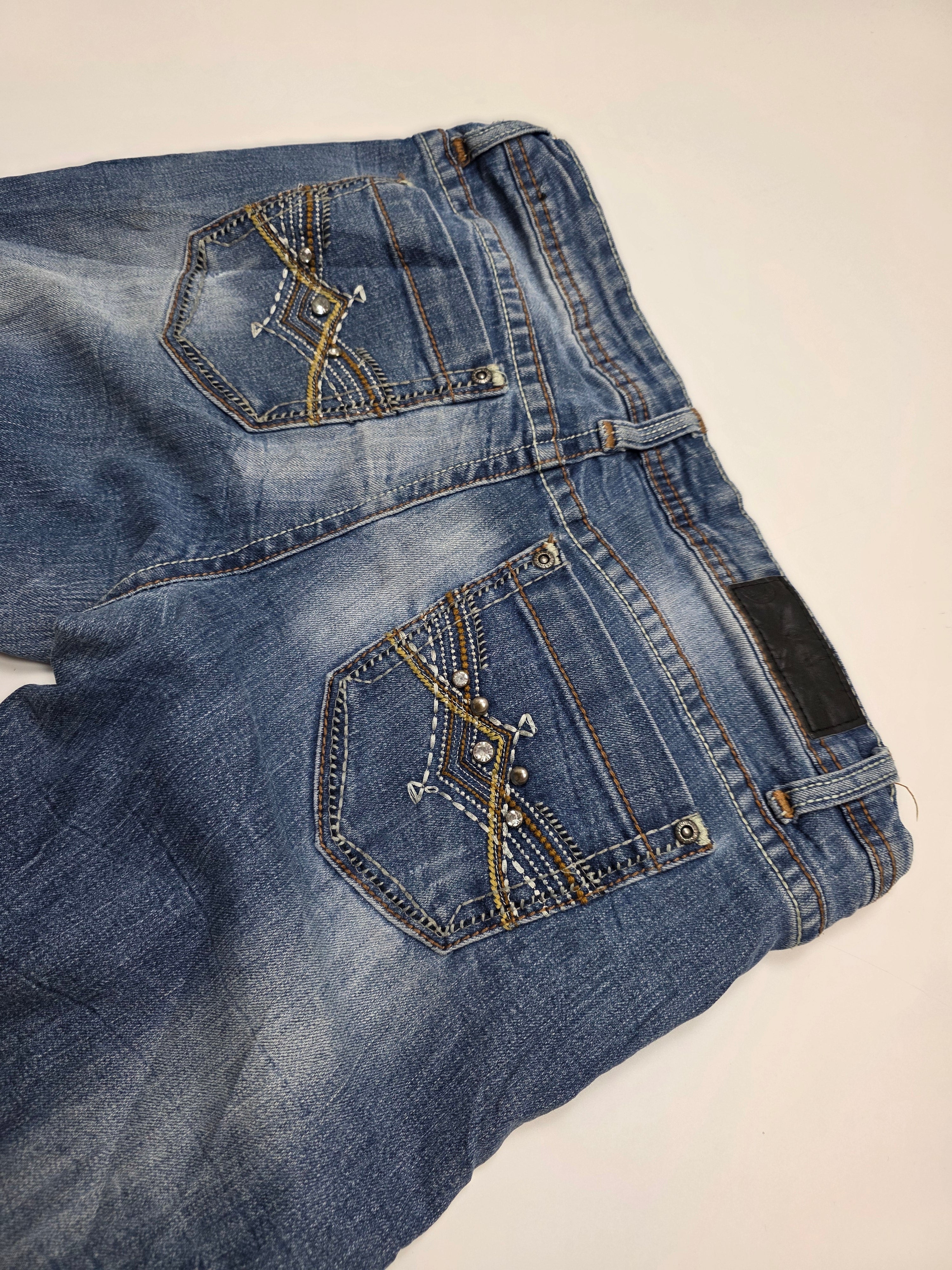 Vintage Jeans im Used-Look mit Ziernähten und Nieten an den Gesäßtaschen auf hellem Hintergrund