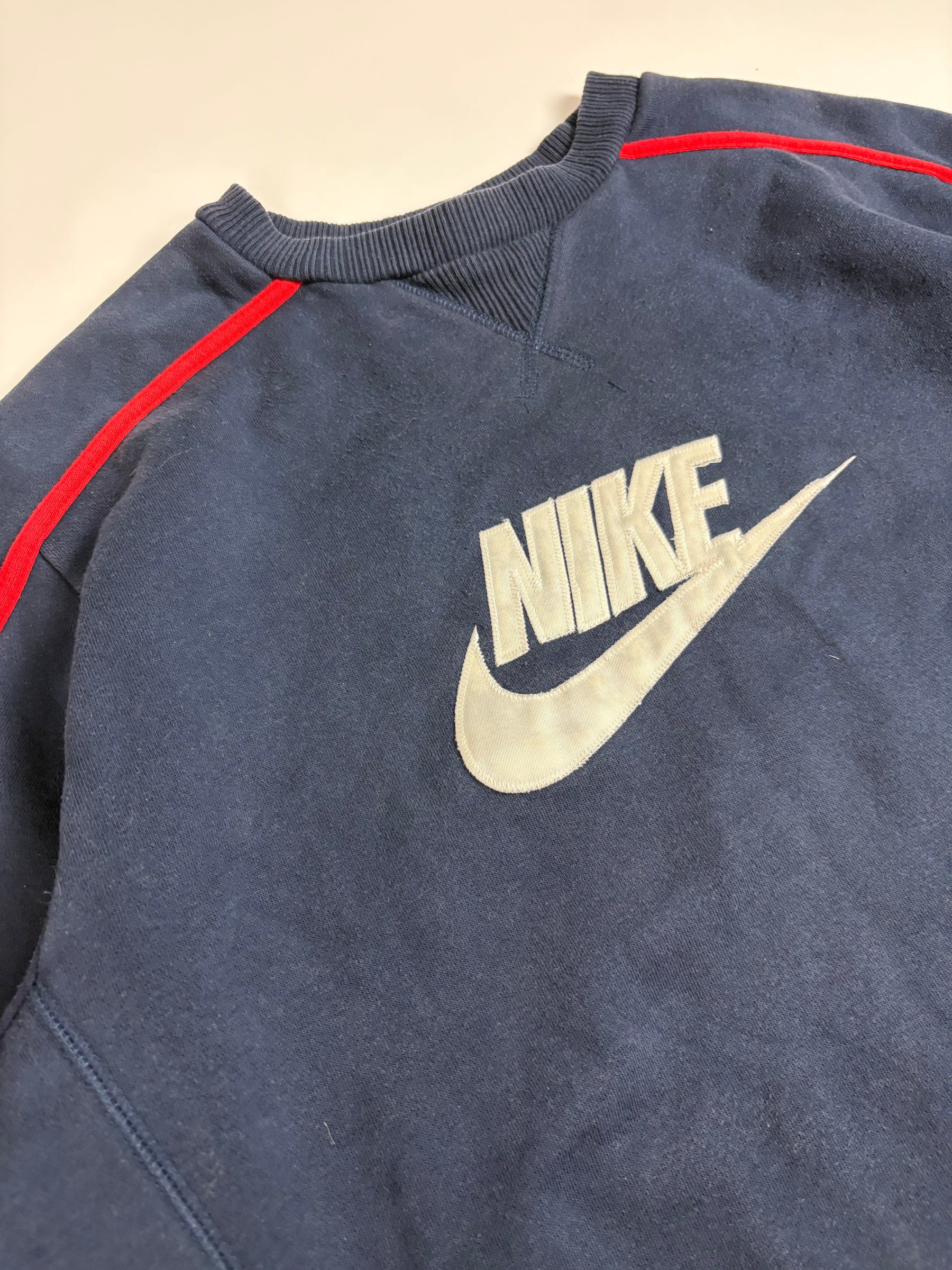 Detail des hellen Nike Logo-Patches und der roten Kontrastdetails am navyfarbenen Vintage Sweater