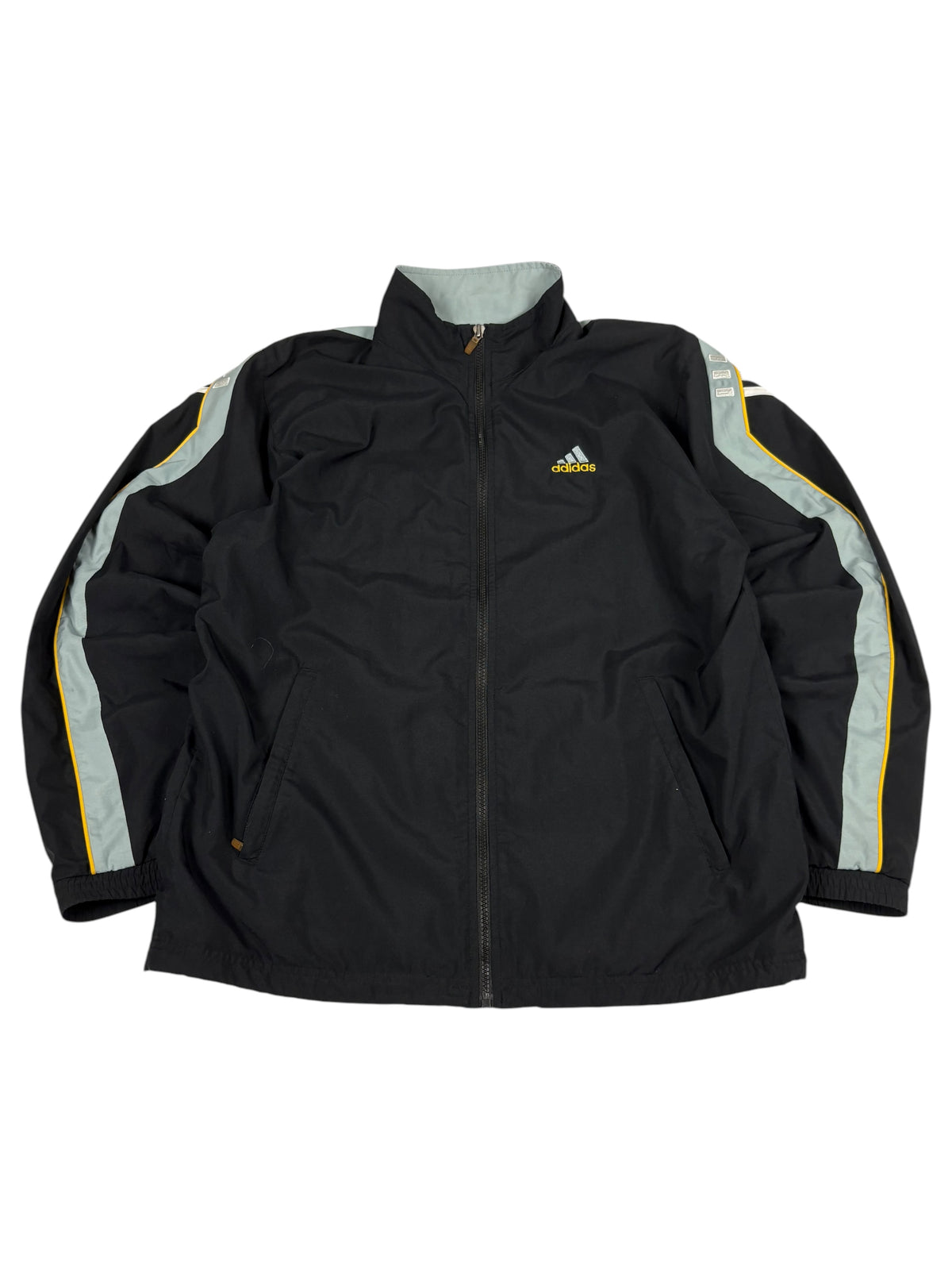 Schwarze Adidas Trackjacket mit hellgrauen Schultereinsätzen, gelben Paspeln und Eingriffstaschen, flach liegend von vorn