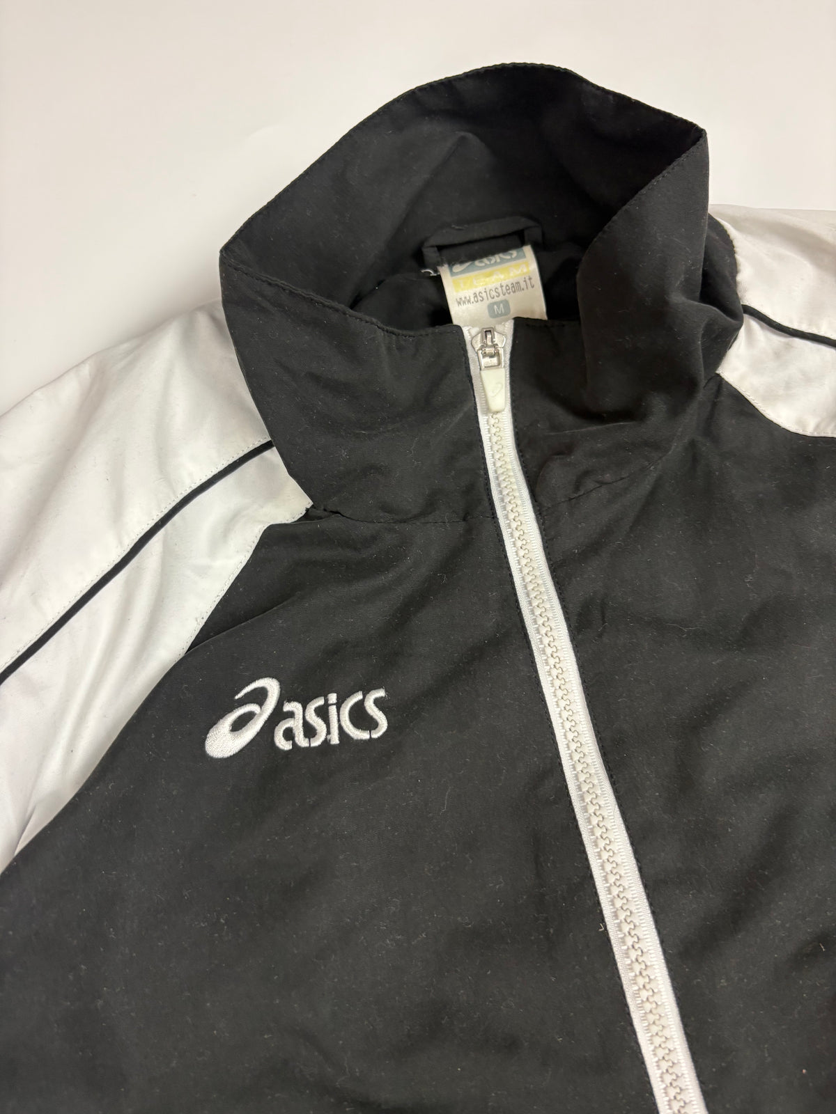 Weißes Asics Brustlogo und Full-Zip an der schwarz-weißen Vintage Trackjacket