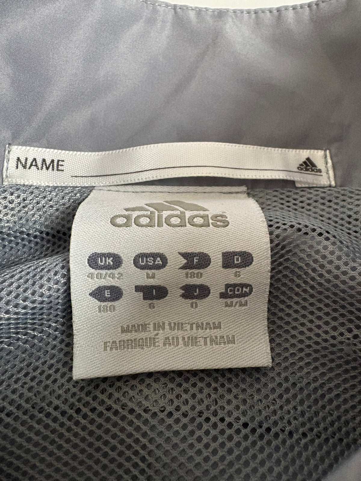 Detailaufnahme des Adidas 3-Streifen Vintage Tracksuits in Grau und Schwarz