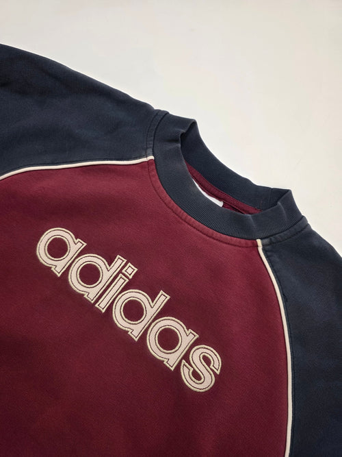 Detail des großen Adidas Frontlogos und der hellen Kontrastpaspel am bordeauxfarbenen Vintage Sweater