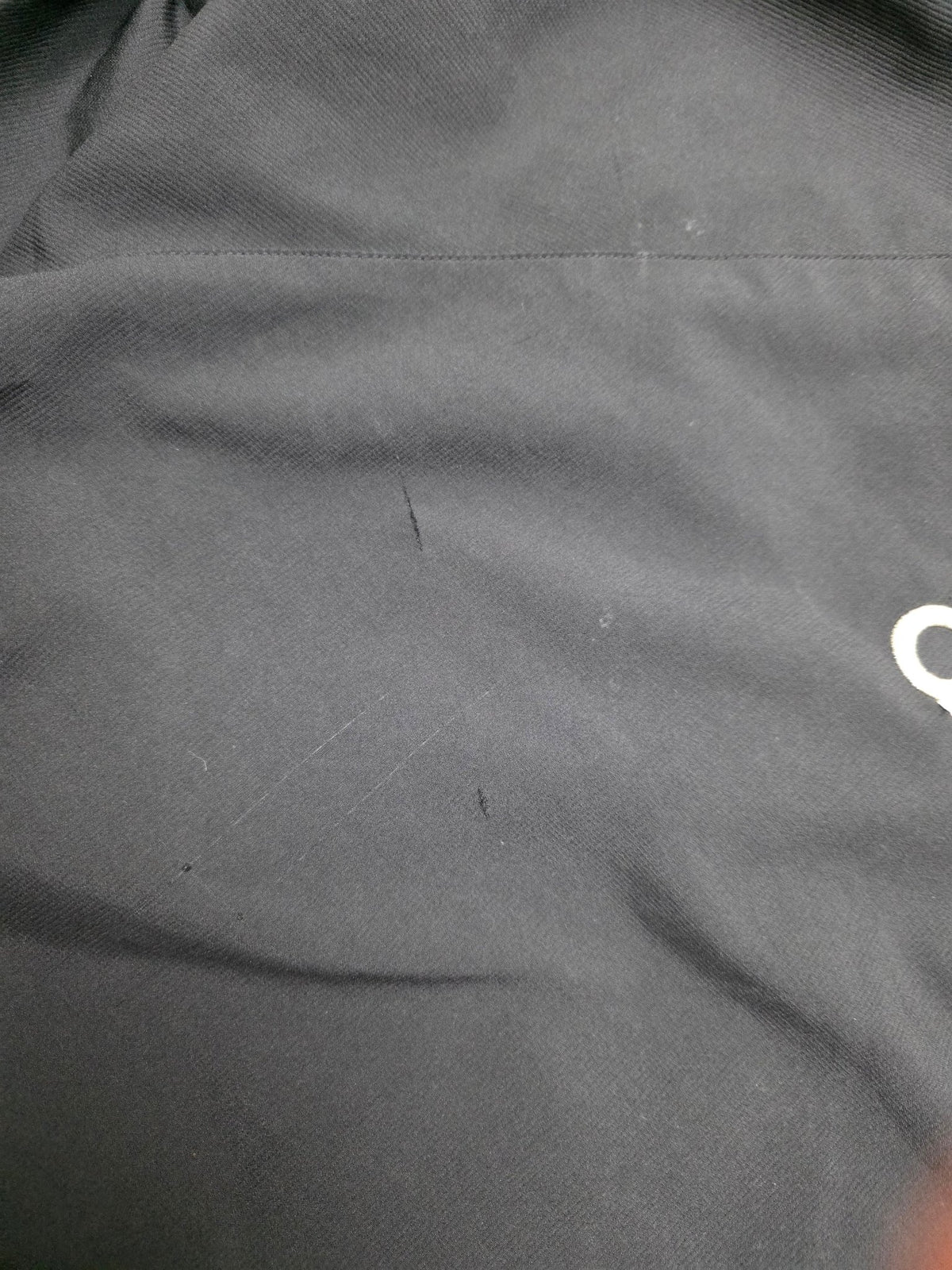 Dokumentierte Kratz- und Oberflächenmarken am schwarzen Stoff der Adidas Big Logo Vintage Trackjacket
