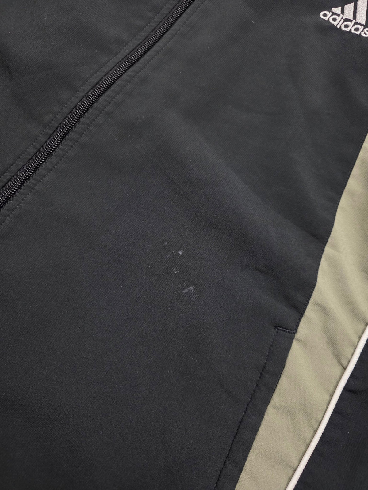 Dokumentierte kleine helle Flecken und Oberflächenspuren auf der schwarzen Adidas Vintage Trackjacket