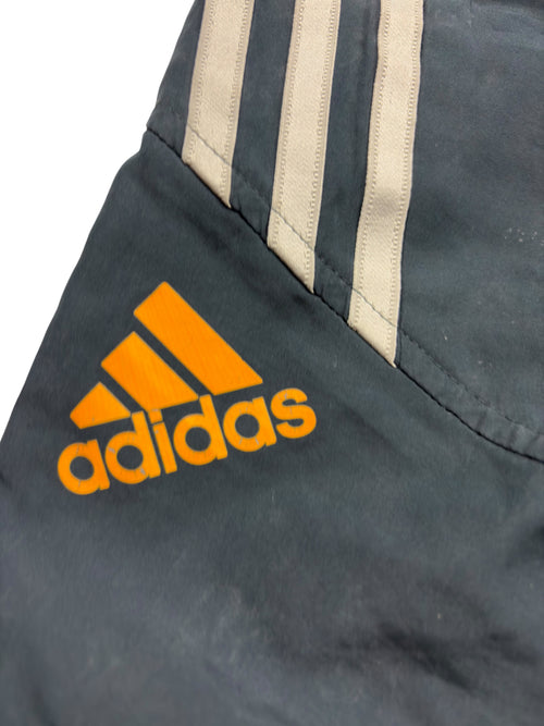 Orangefarbenes Adidas-Logo und beige 3-Streifen auf navyfarbenen Shorts