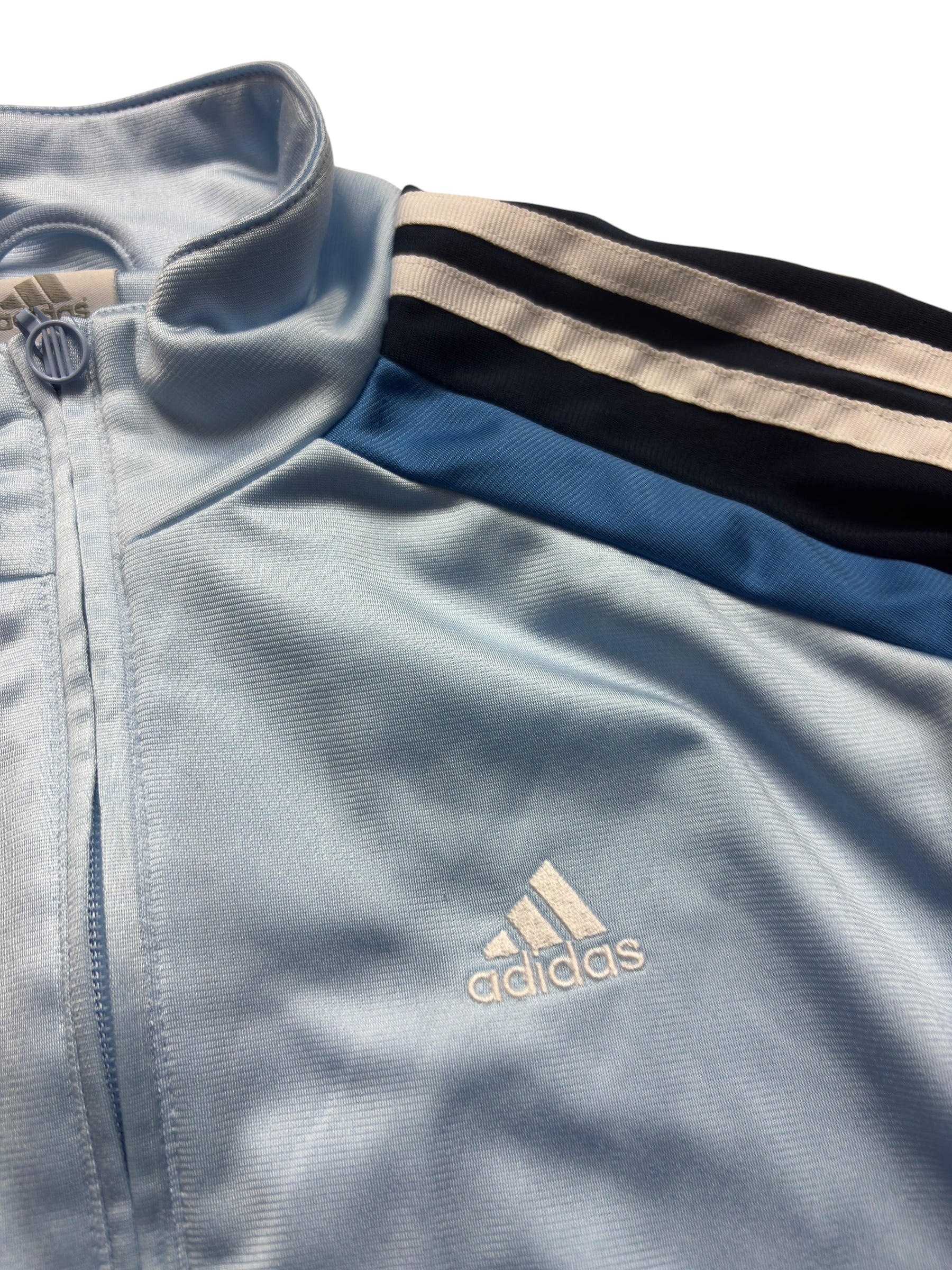 Weißes Adidas Brustlogo, blaue Schulterpanels und Three Stripes an der babyblauen Vintage Trackjacket