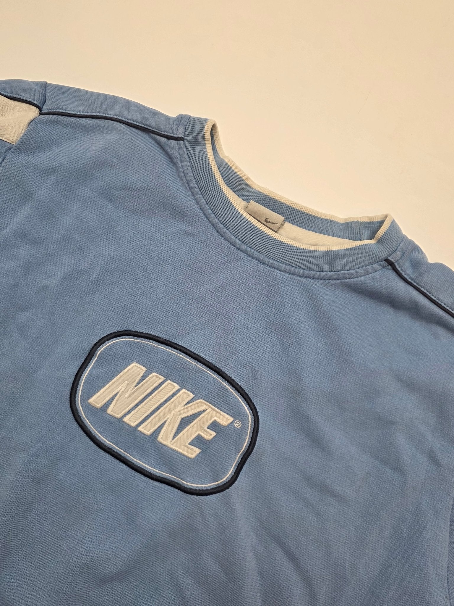 Nike Sweater Detailansicht Rundhalskragen mit ovalem Brustpatch und dunkler Schulterpaspel