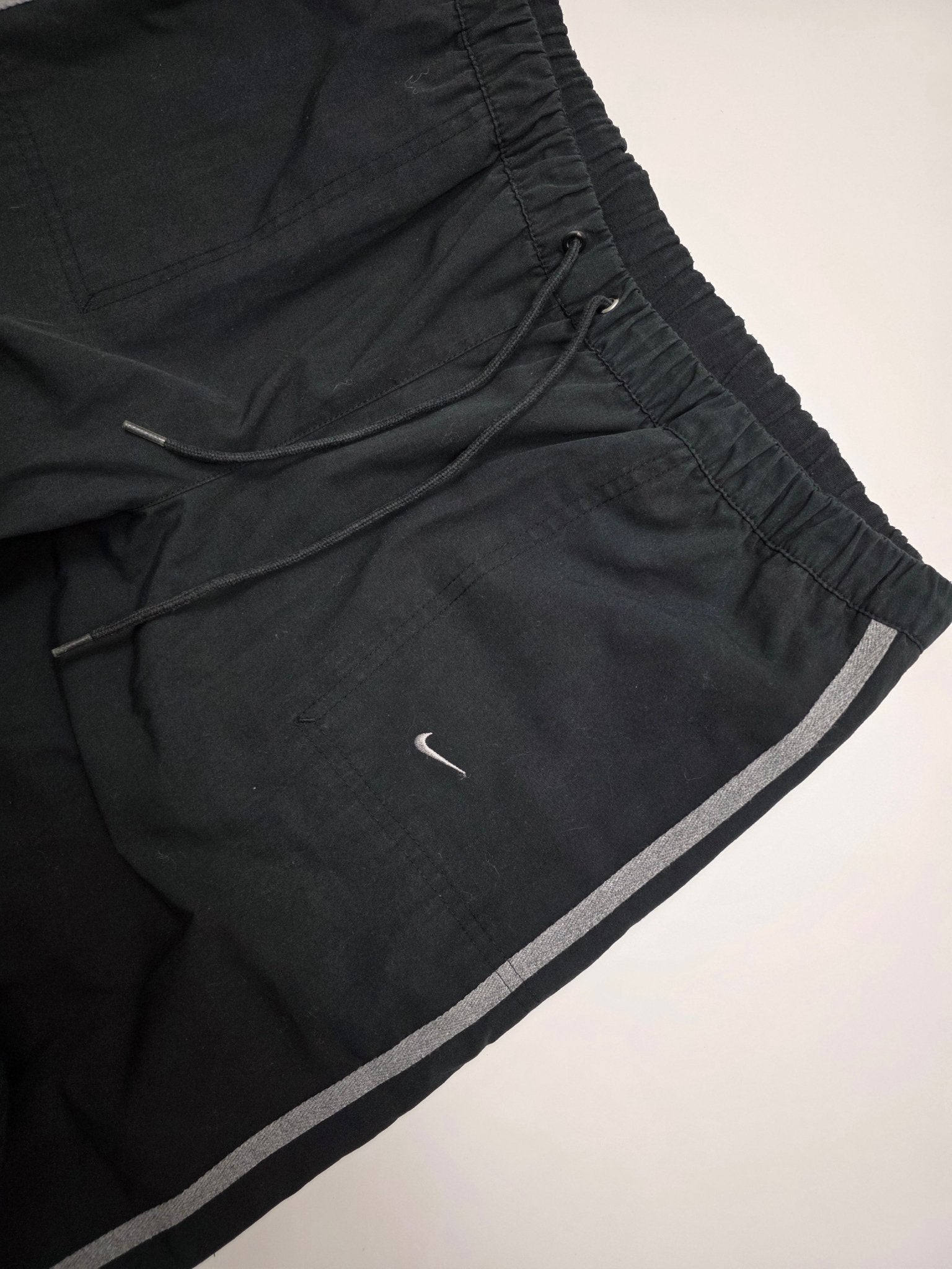Detail von elastischem Kordelzugbund, Mini Swoosh und grauem Seitenstreifen an den Nike Vintage Trackpants