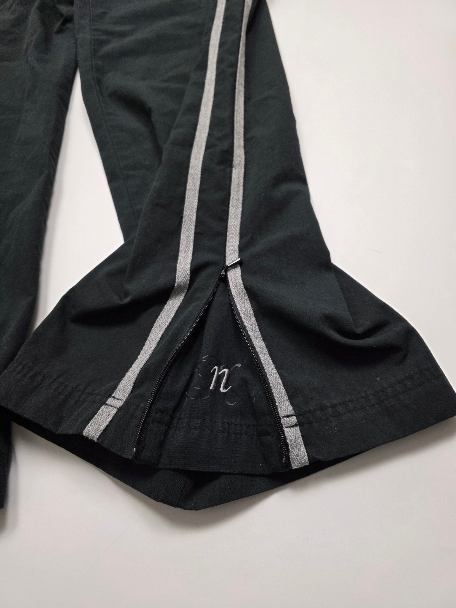 Geöffneter Reißverschluss am Beinabschluss und doppelte graue Seitenstreifen der Nike Vintage Trackpants