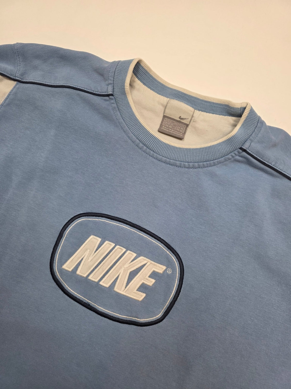 Detail des ovalen NIKE Brustpatches und der cremefarbenen Schulterpanels am Vintage Sweater