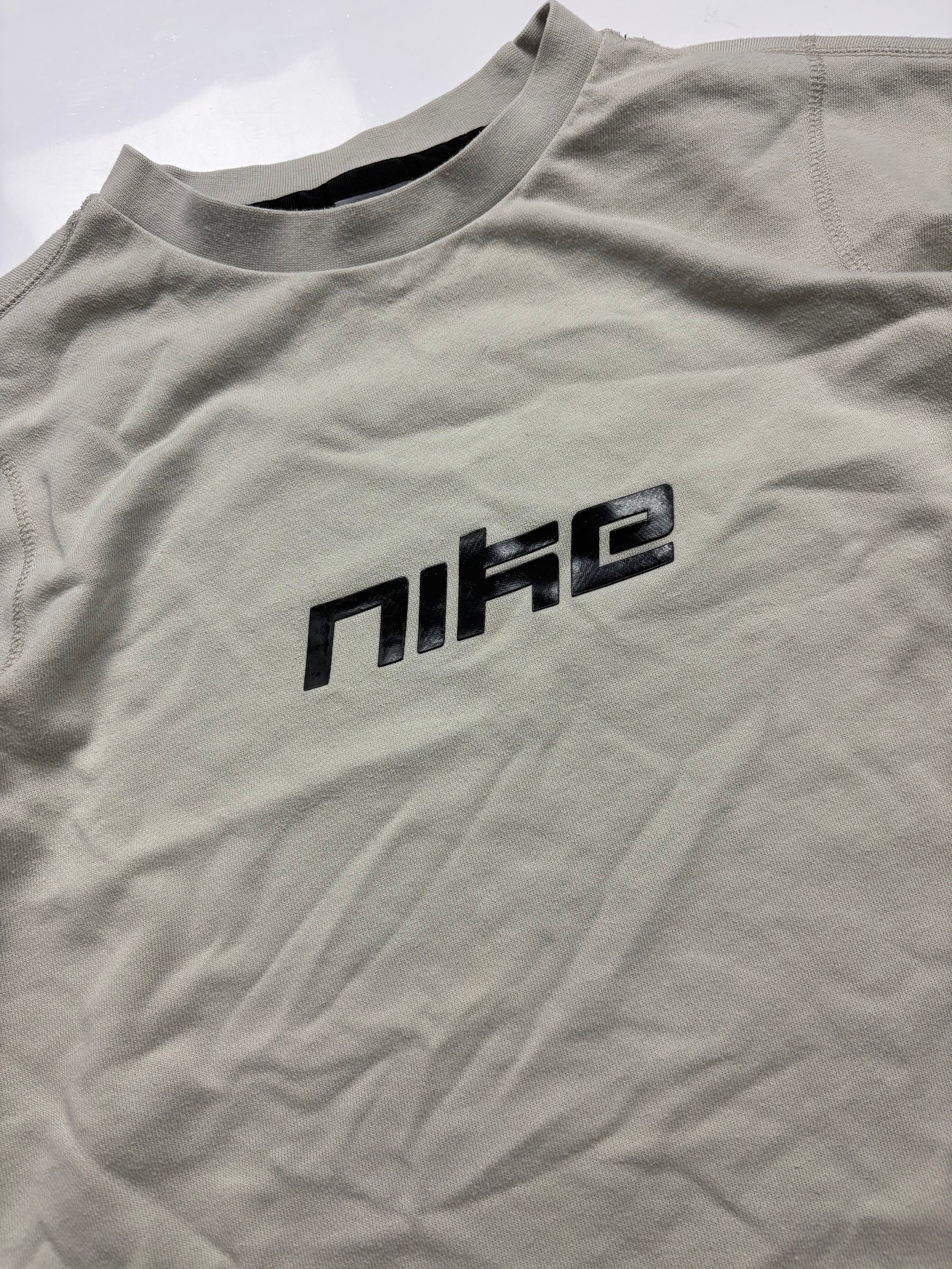 Detail des schwarzen Nike Spellout Logos auf dem hellgrauen Vintage Sweater