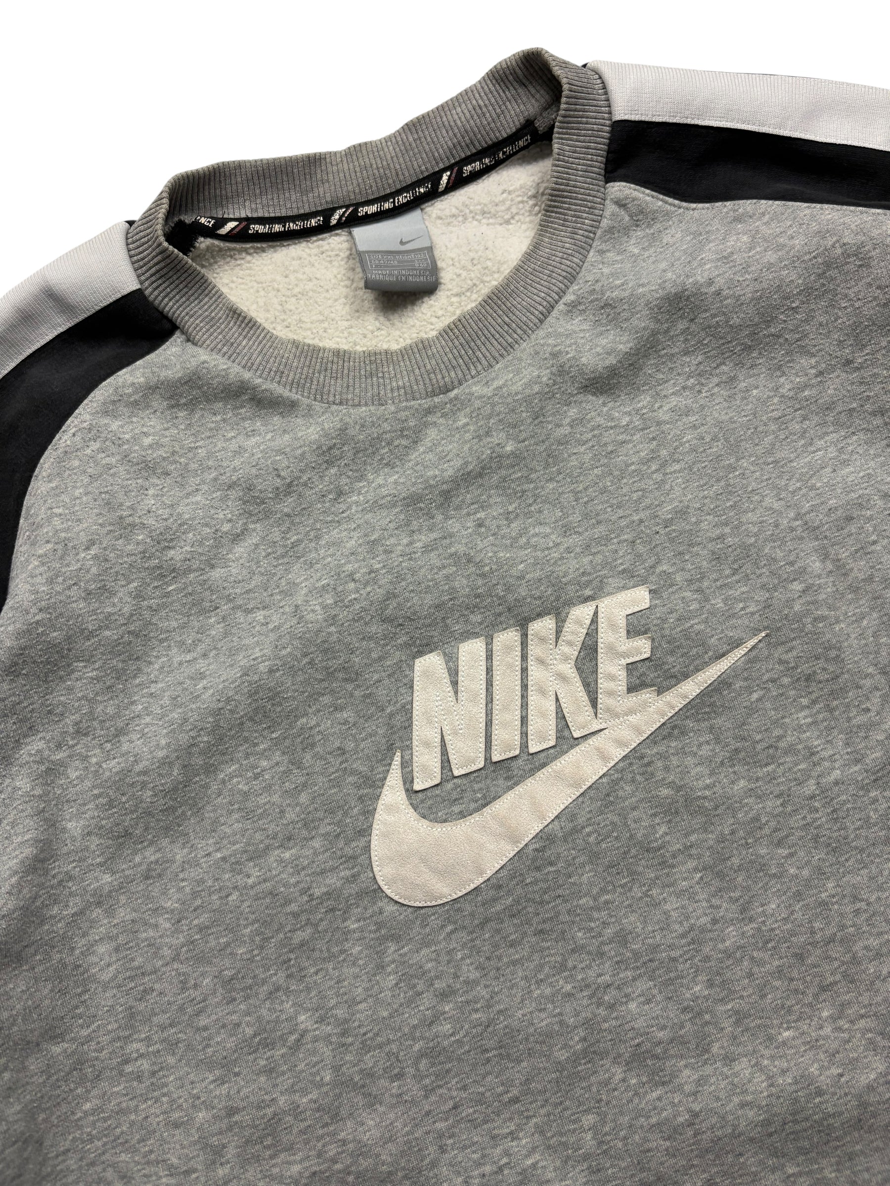 Detail des großen weißen Nike Swoosh Frontlogos am grauen Sporting Excellence Vintage Sweater