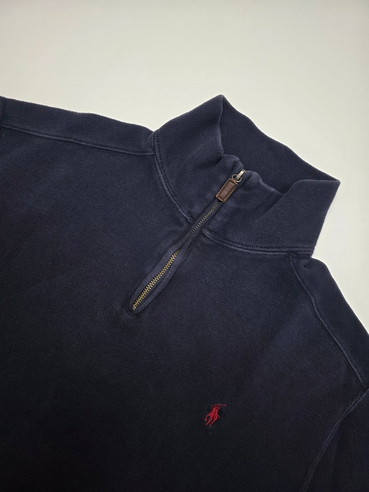 Detail des roten Polo Ralph Lauren Brustlogos, Half-Zips und Leder-Pulltabs am navyfarbenen Sweater