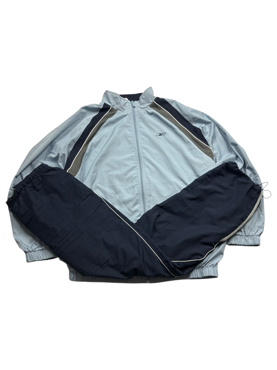 Reebok Vector 90s Tracksuit Jacke Hellblau Größe XL – Frontansicht mit dunklen Einsätzen und weißem Piping