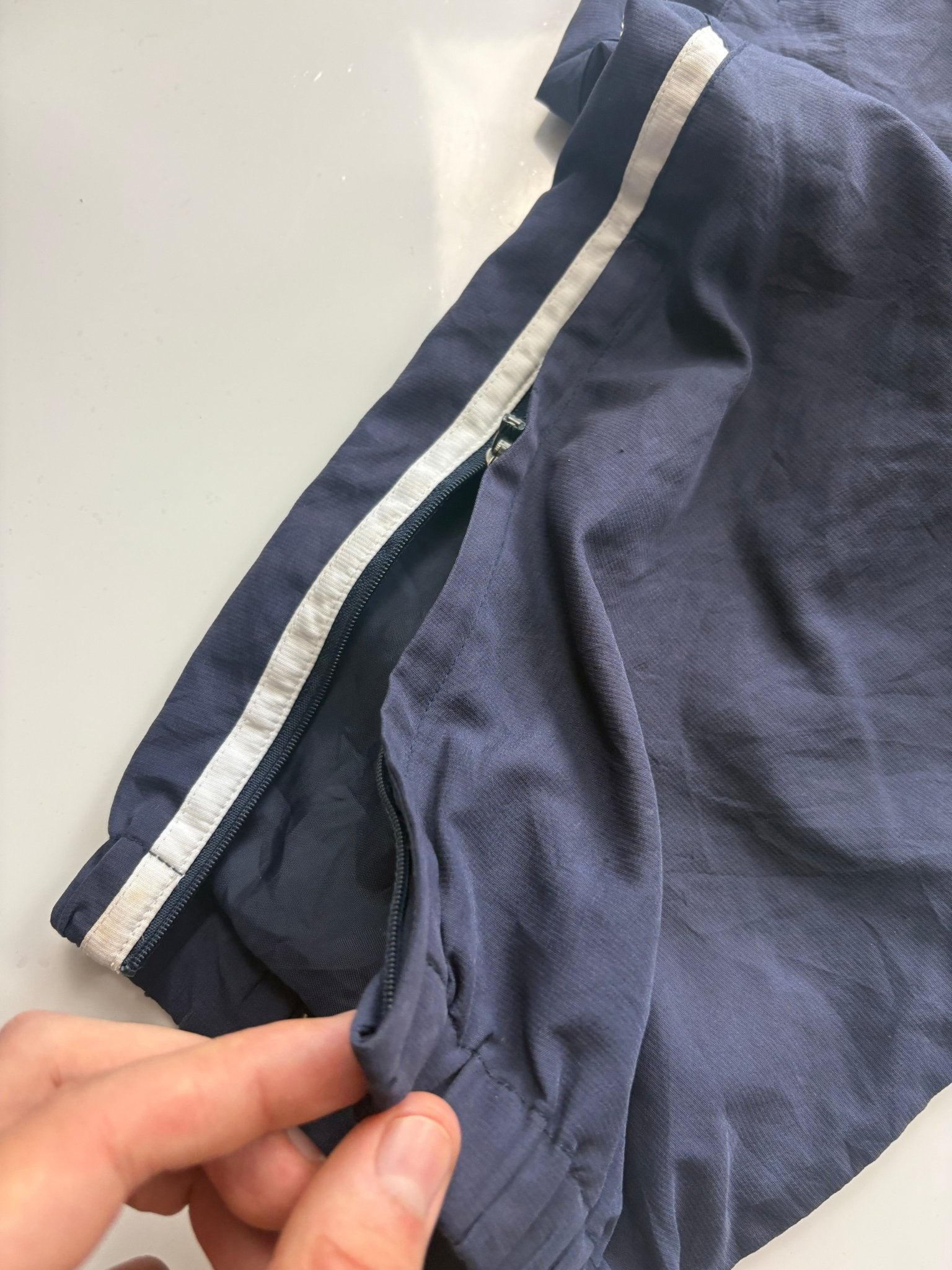 Detail des Knöchelzips, weißen Seitenstreifens und Beinabschlusses der Umbro England Vintage Trackpants